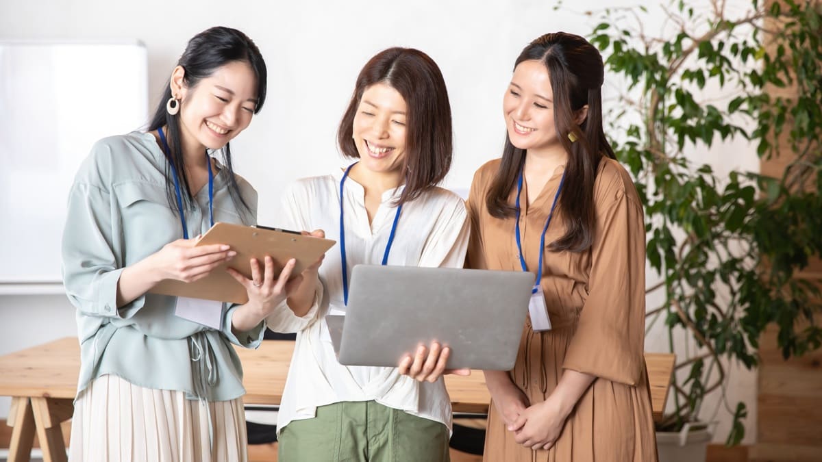 女性3人が談笑してパソコンをみている