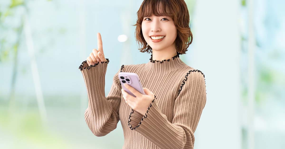 スマホを見て指を立てる女性